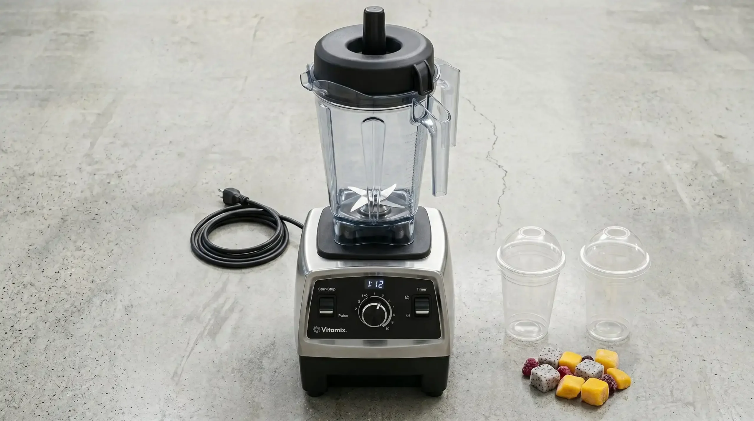 Liquidificador industrial de alta potência e copos biodegradáveis sobre balcão de cimento polido, representando infraestrutura profissional para smoothies.